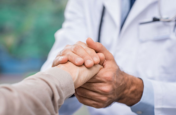 A physician holding another's hand compassionately.