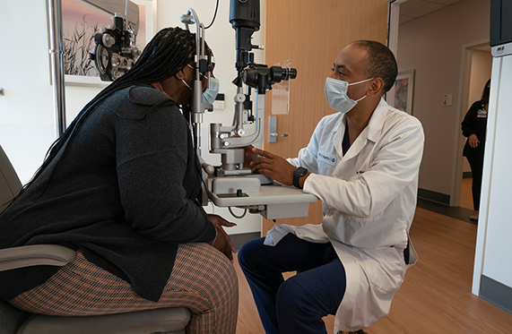 A male physician conducting an eye exam on a female patient
